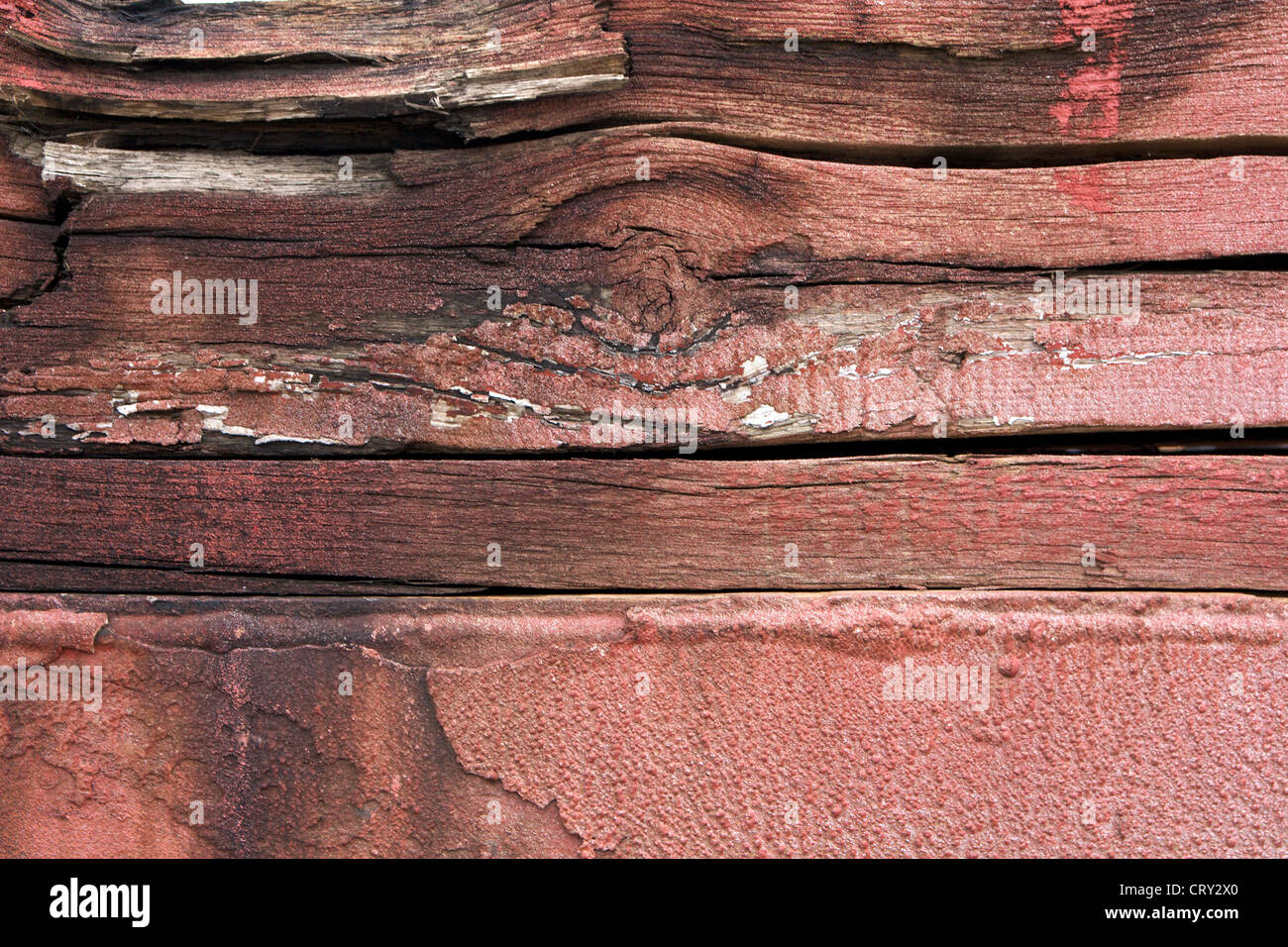 Stacked wooden beams with faint, flaking red paint at an industrial facility. Stock Photo
