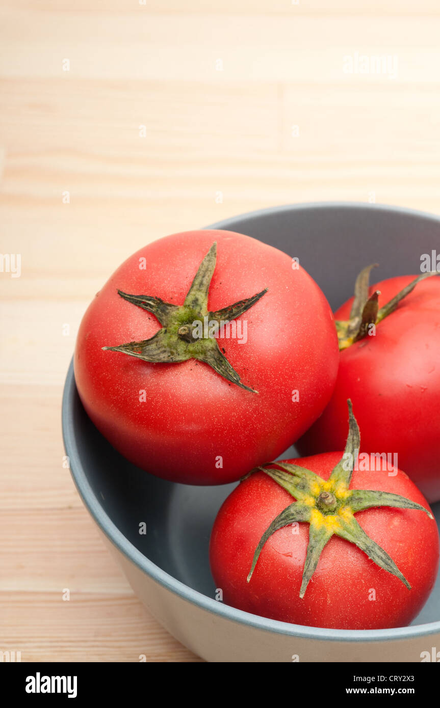 fresh ripe tomatoes on a blue bowl over pine wood table Stock Photo - Alamy