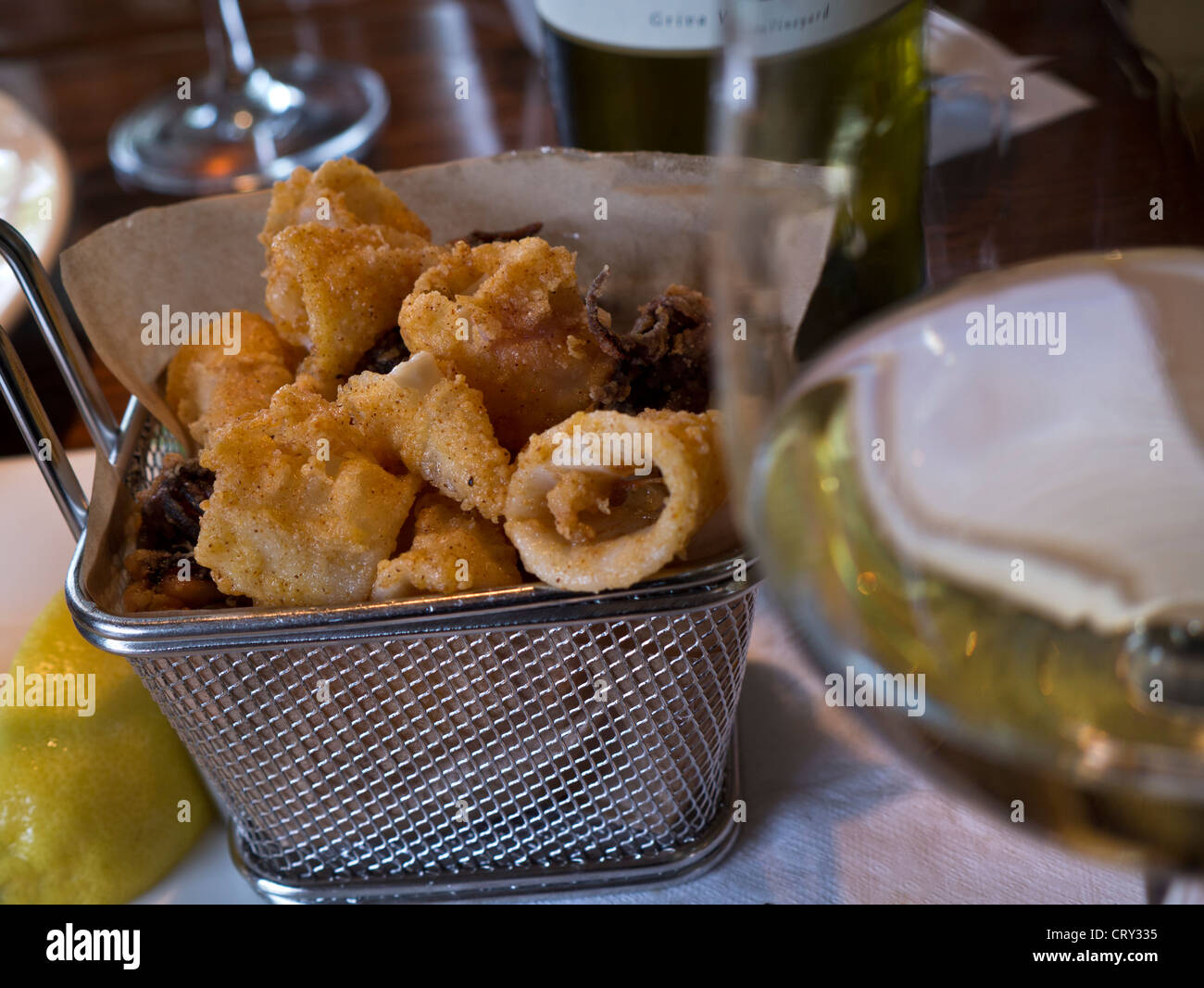 Fried calamari tapas in basket food, POV with glass of Bernardus Sauvignon Blanc, on table in renowned Rio Grill bar restaurant Carmel California USA Stock Photo