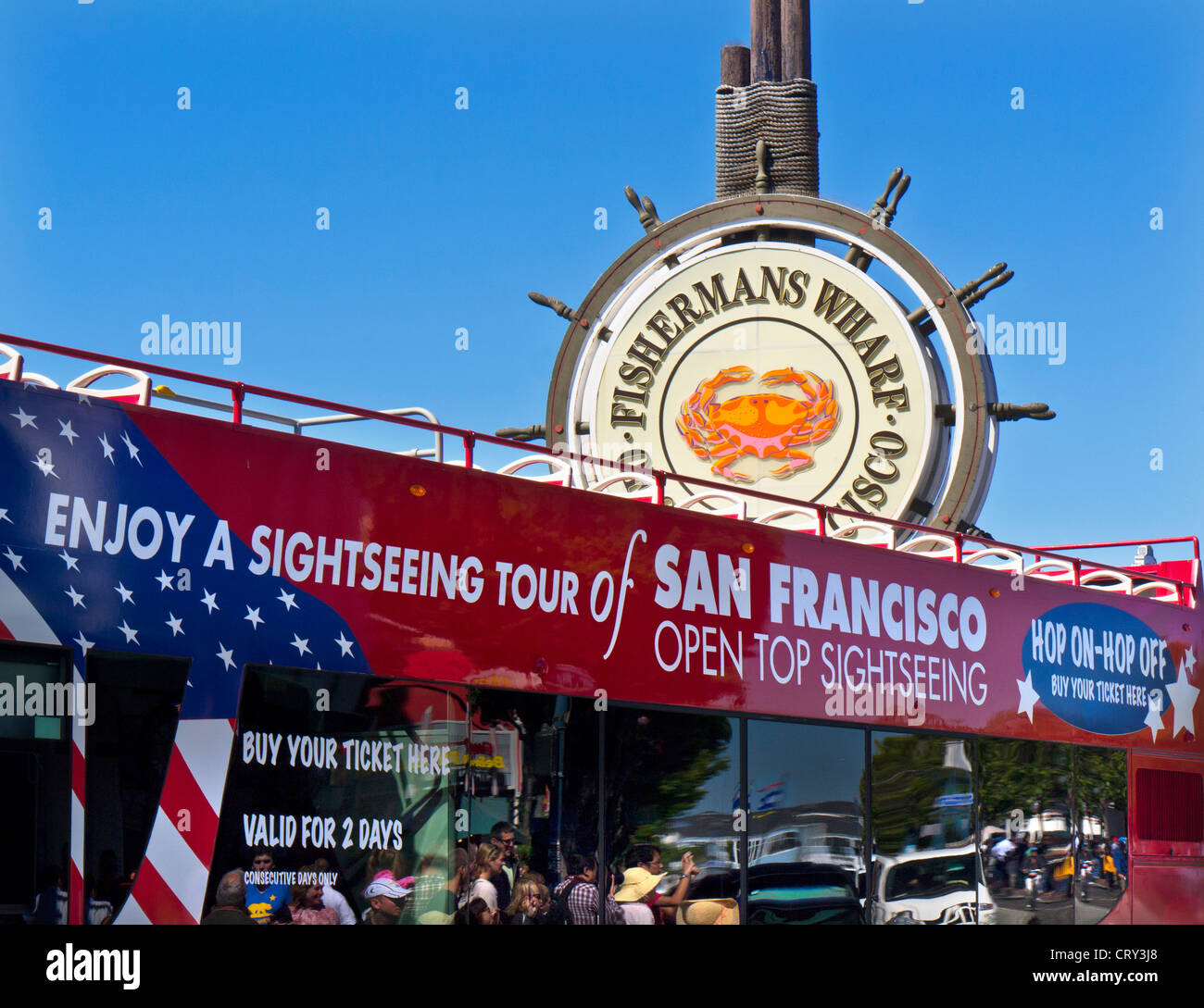 Open top red city tour bus at Fisherman's Wharf sign with tourists reflected in tinted windows San Francisco California USA Stock Photo