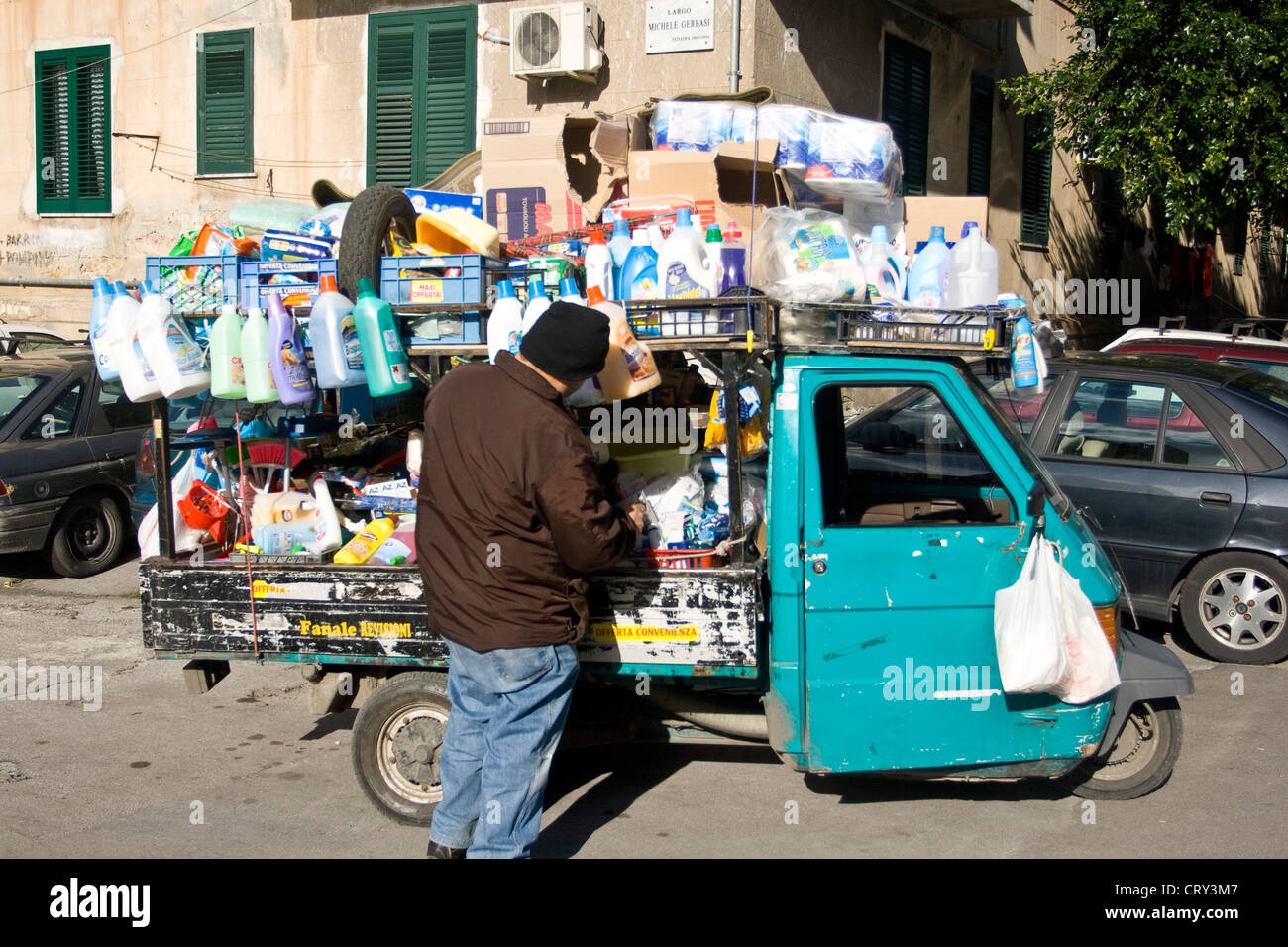 Street scene: man selling goods in a mini van Piaggio Ape, Palermo, Sicily, Italy. Stock Photo