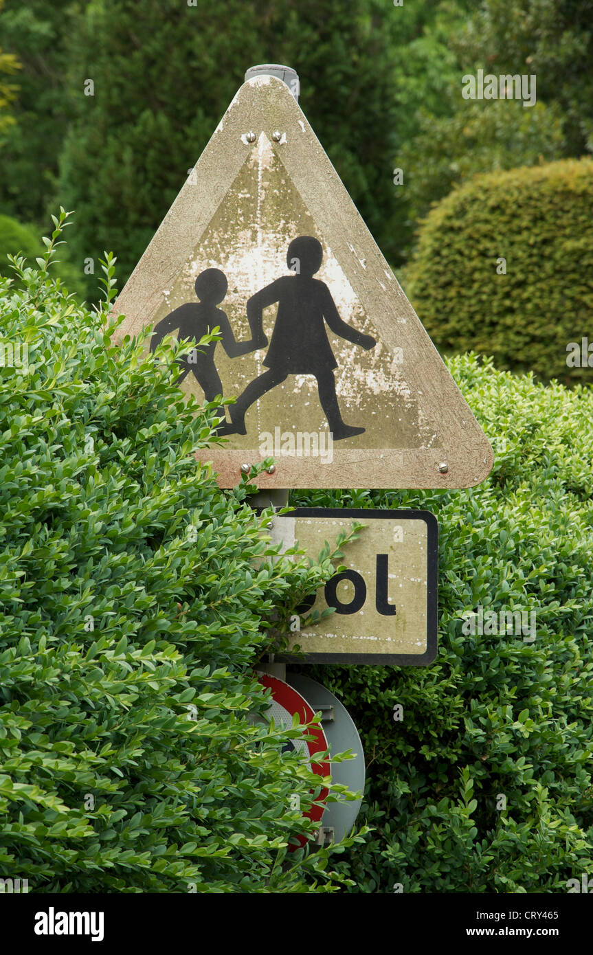 The 'school children crossing' sign is a British design classic. This pleasing faded and weathered example is at Milton Abbas, in Dorset. England, UK. Stock Photo