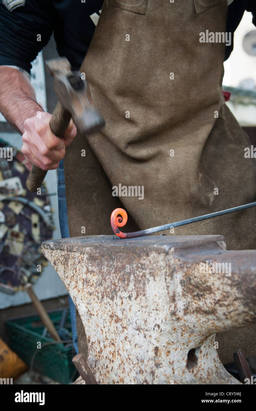 Blacksmith making decorative iron work using hammer and anvil Stock Photo