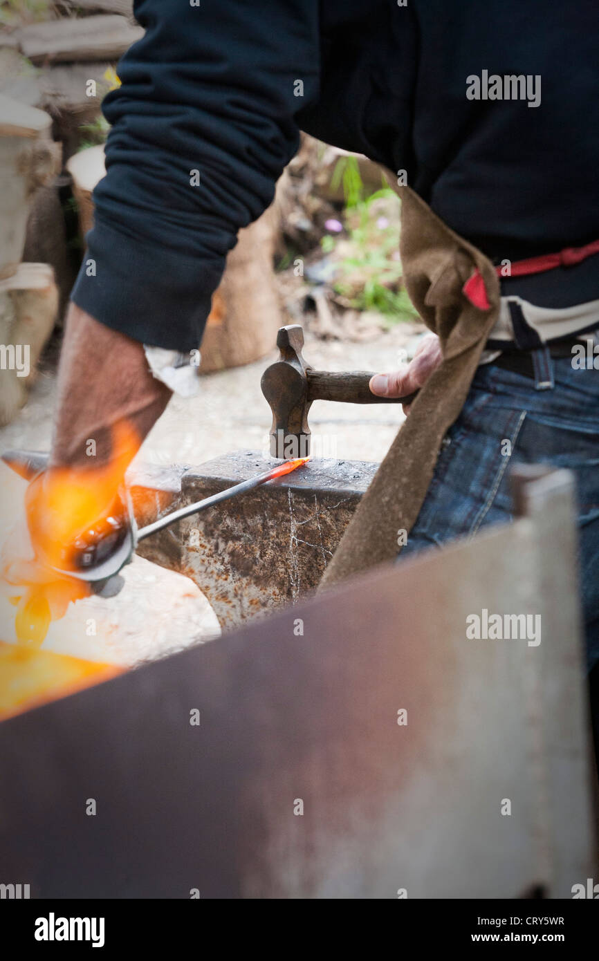 Blacksmith making decorative iron work using hammer and anvil Stock Photo