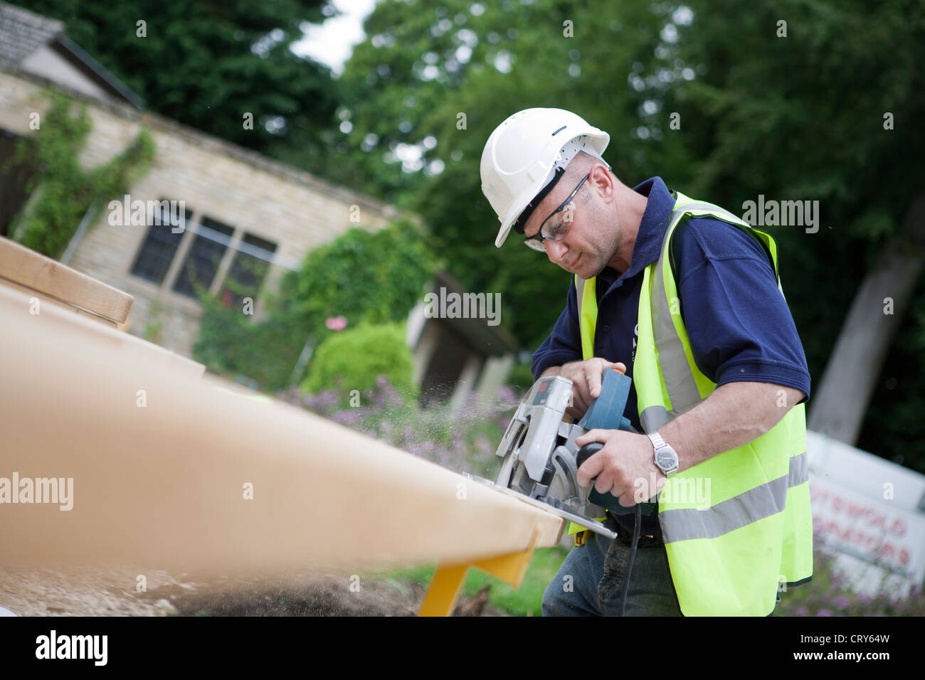 Builder using a circular saw to cut rafters to size on a building site. Stock Photo