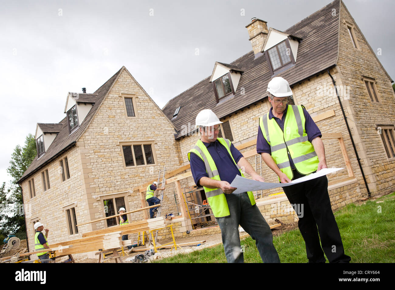 Site manager discusses plans with surveyor on building site Stock Photo