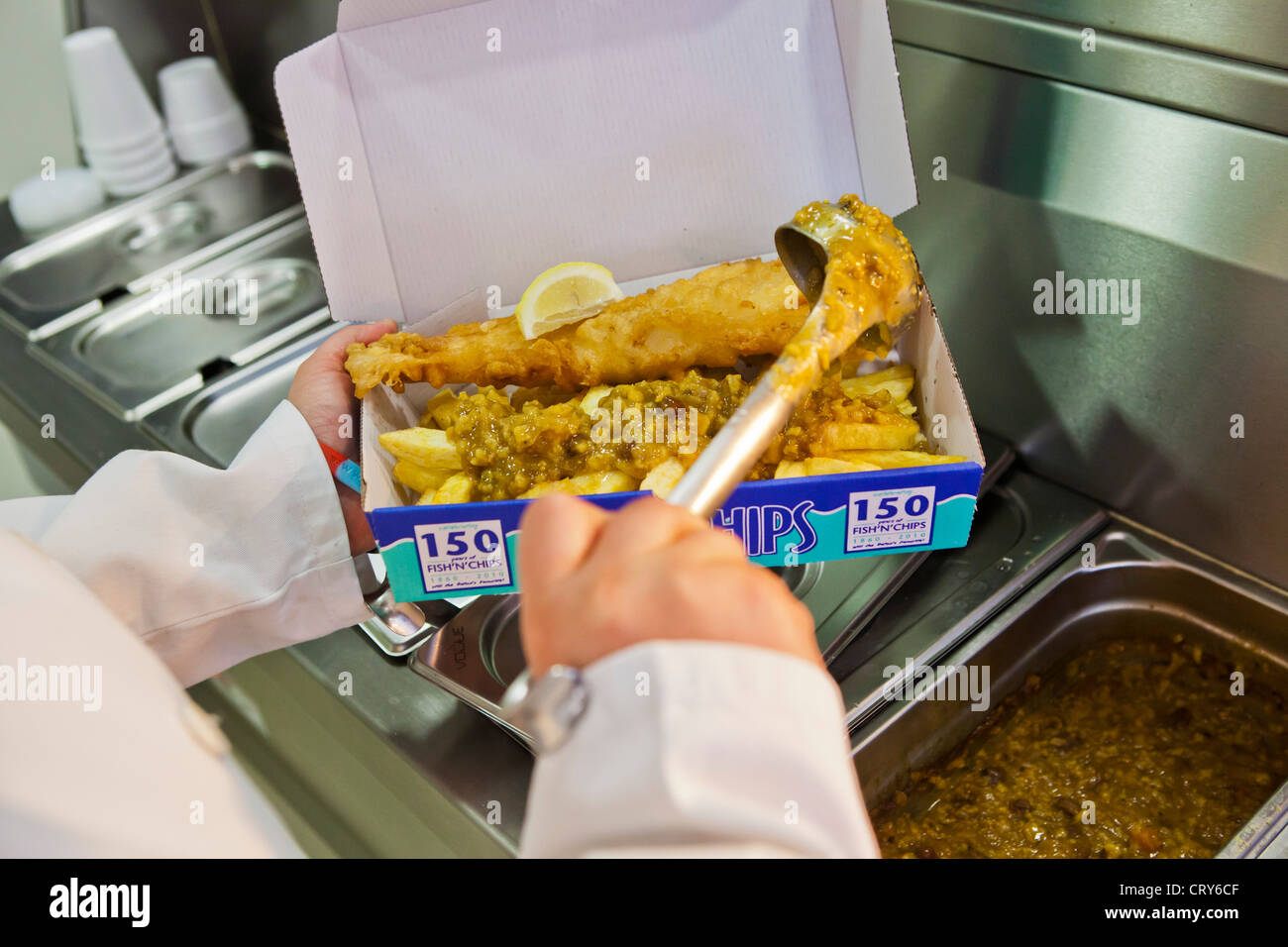 Curry sauce being added to fish and chips Stock Photo - Alamy