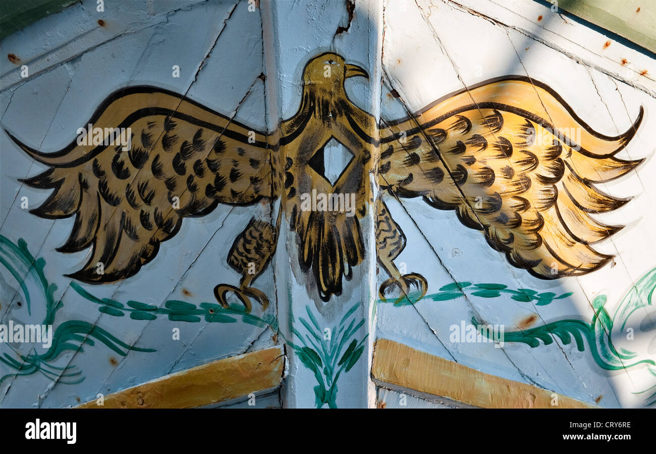 A flamboyant eagle painted on a fishing boat used by refugees to cross the Mediterranean from North Africa, at the port of Pozzallo, Sicily, Italy Stock Photo