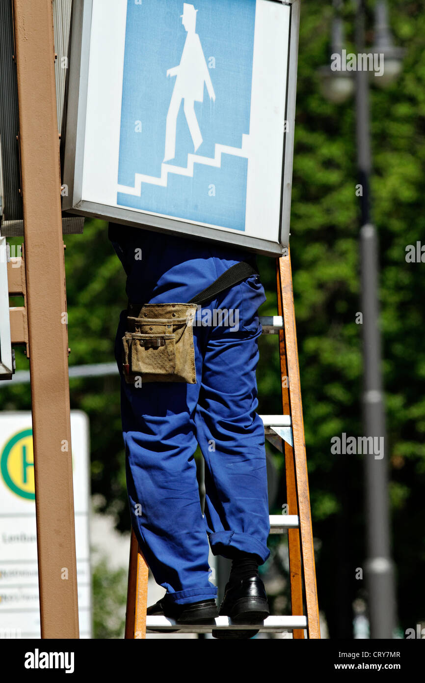 Man standing on a ladder servicing a sign, Munich Upper Bavaria Germany Stock Photo