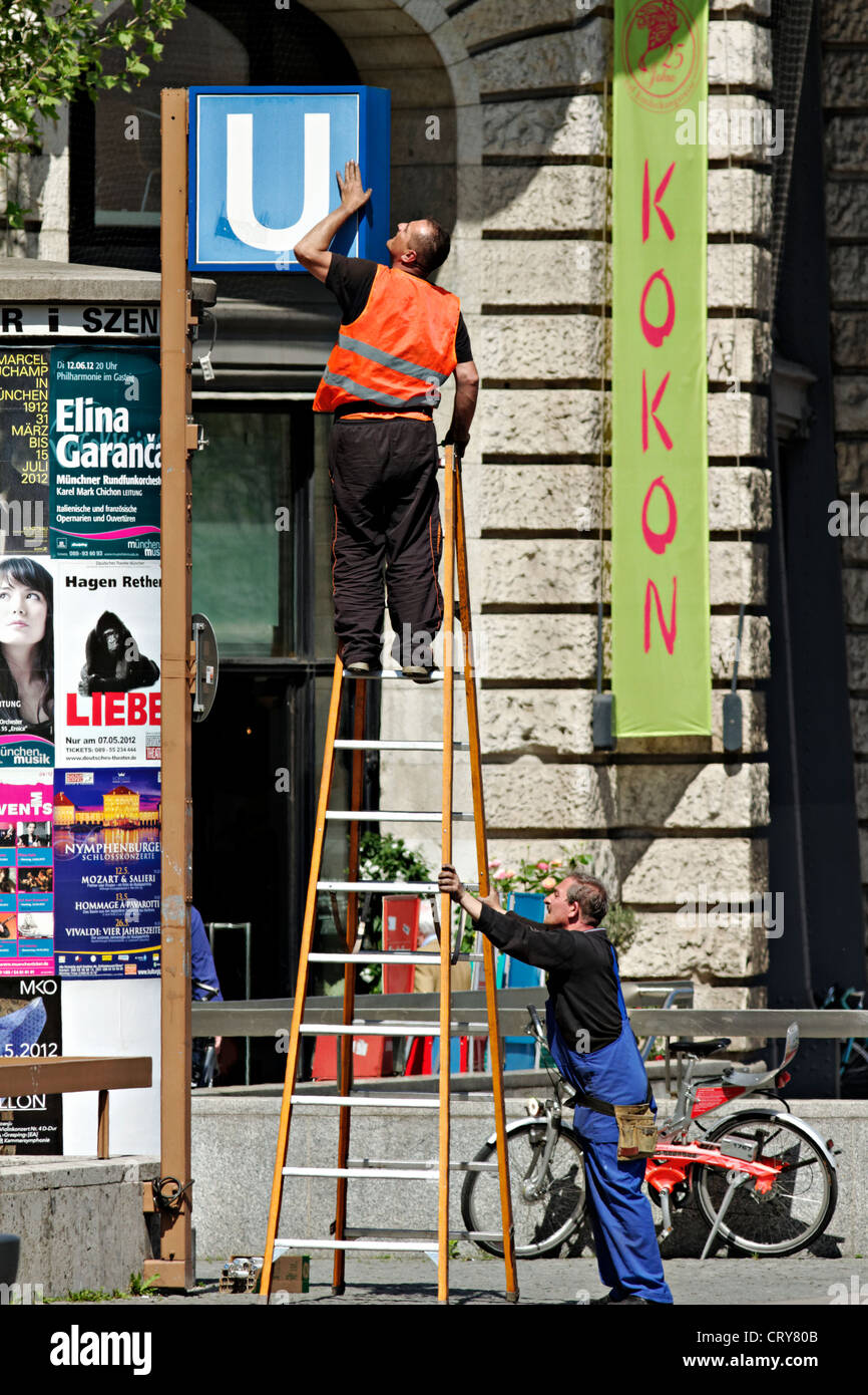 Man standing on a ladder servicing a sign Stock Photo