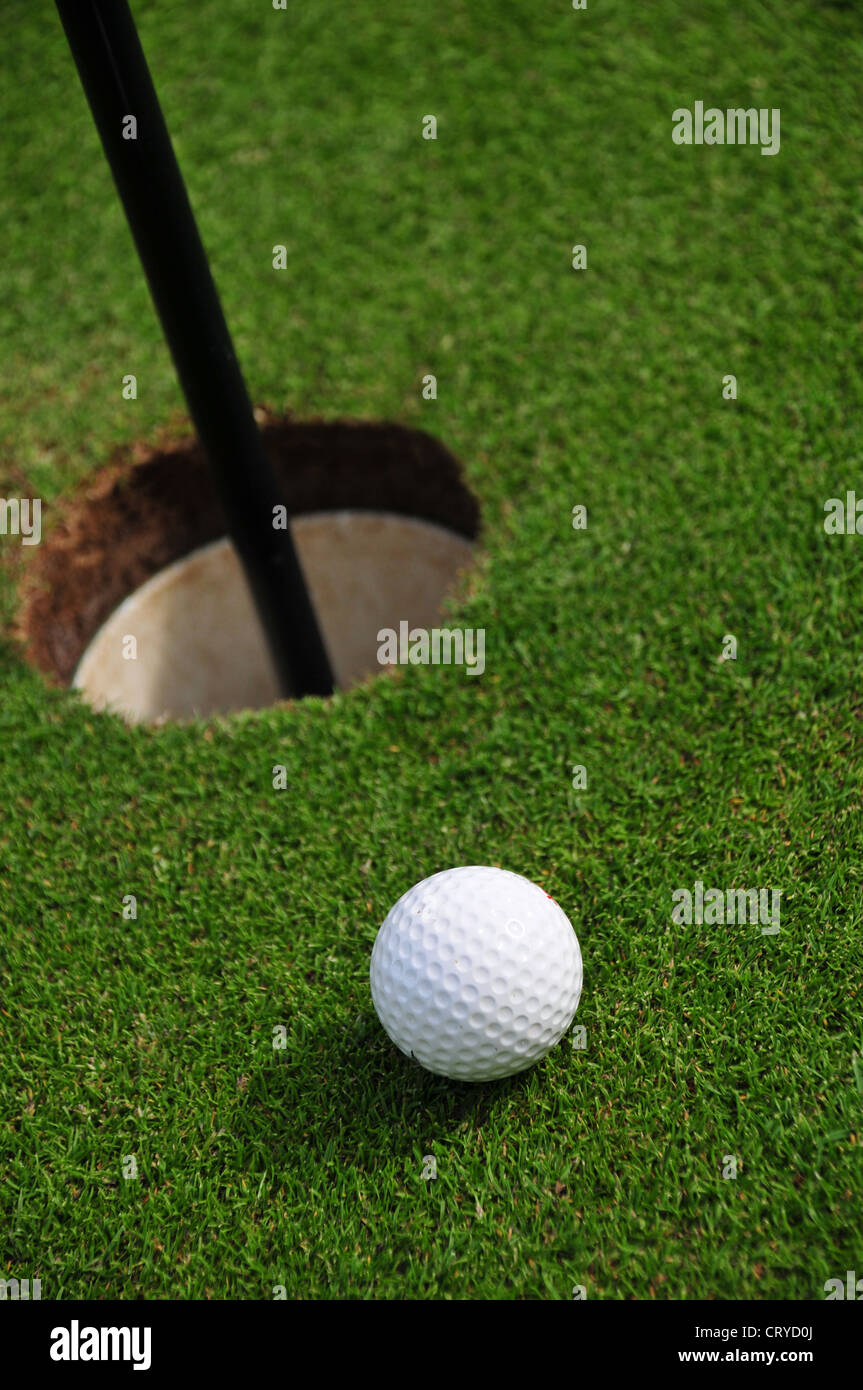 A golf ball close to a golf hole seen from close by Stock Photo