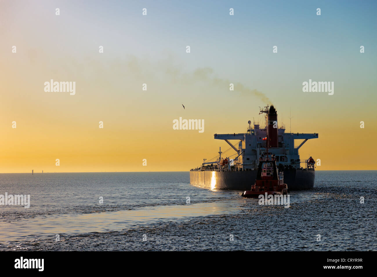 Tanker at sunset putting out to sea. Stock Photo