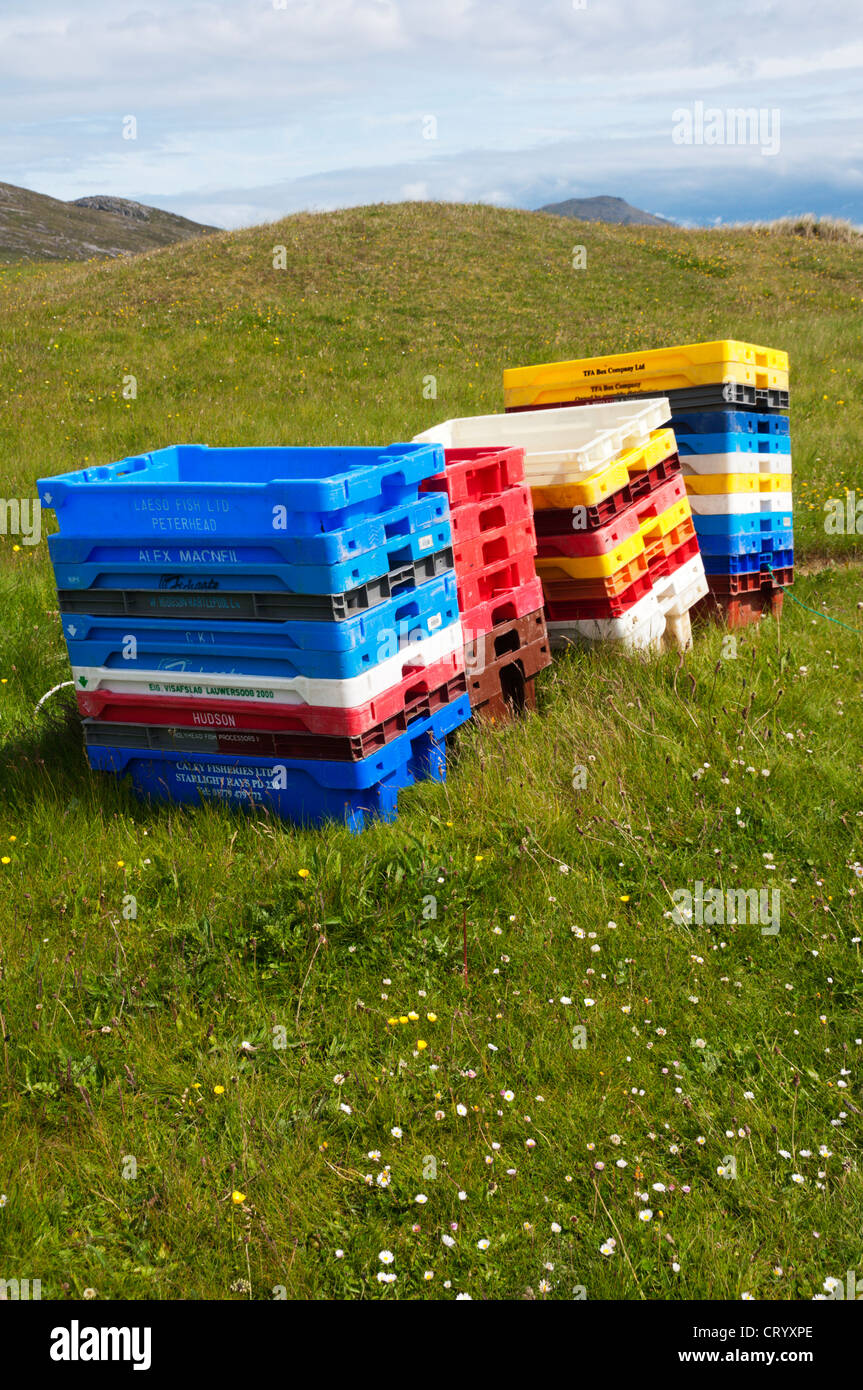 Colourful empty fish boxes stacked on the machair on the Hebridean island of Vatersay. Stock Photo