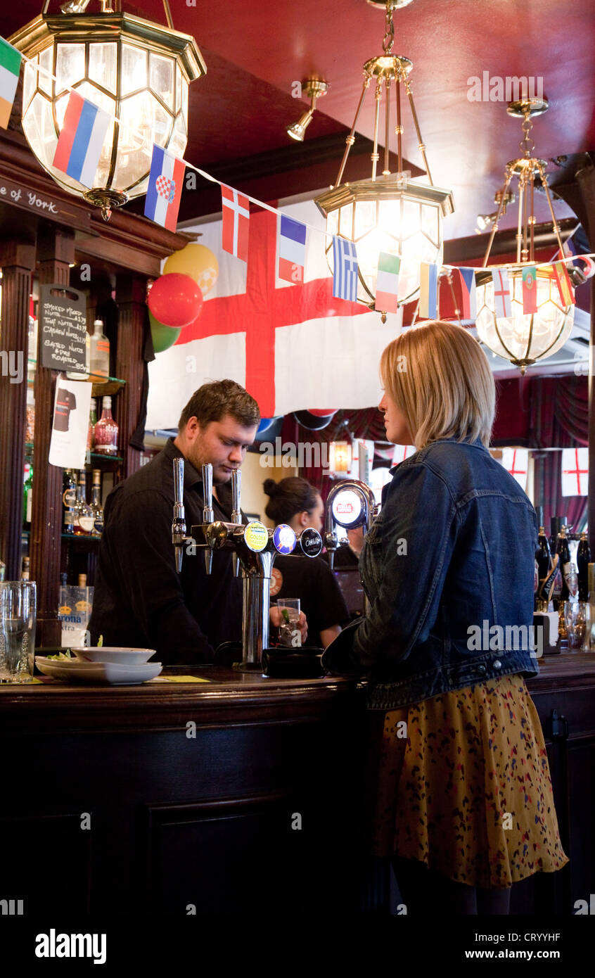 Young woman buying a drink drinks at the bar, interior  of the Duke of York pub, Victoria, London UK Stock Photo