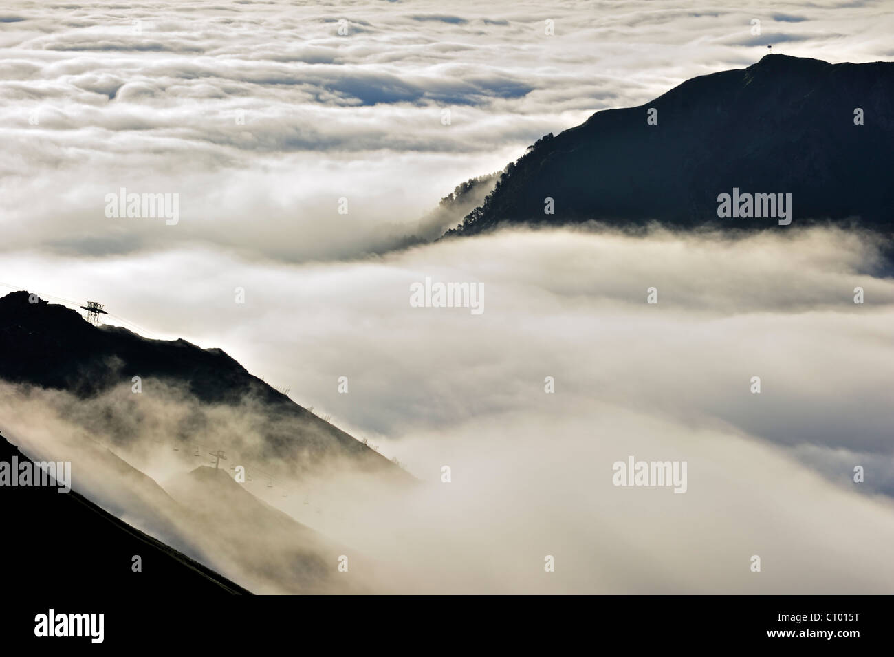 View over silhouetted chairlifts and mountains covered in mist at sunrise seen from the Col du Tourmalet, Pyrenees, France Stock Photo
