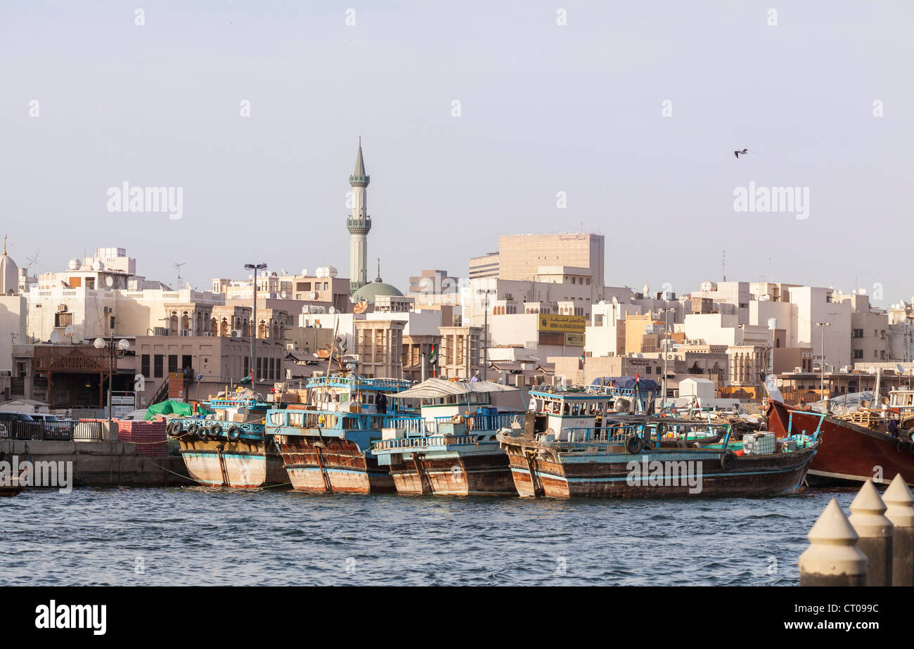 Dhows moored at Dubai Creek, Dubai, UAE with city skyline and minaret Stock Photo