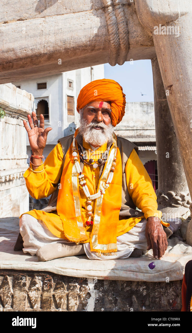 Sadhu, Indian Hindu holy man, dressed in typical saffron robes and orange turban giving a blessing at Jagdish Temple in Udaipur, Rajasthan, India Stock Photo