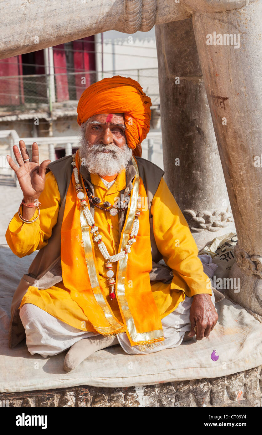 Sadhu, Indian Hindu holy man, dressed in typical saffron robes and orange turban giving a blessing at Jagdish Temple in Udaipur, Rajasthan ,India Stock Photo