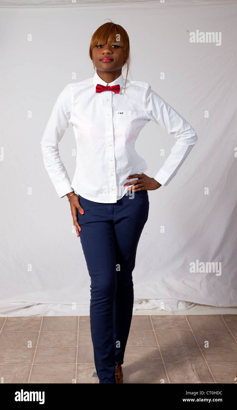 Lovely Black woman in white shirt, red bow tie and blue pants, standing  with her hands on her hips and a serious expression Stock Photo - Alamy
