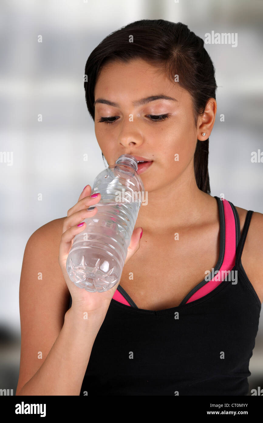 Teen girl drinking water at the gym Stock Photo