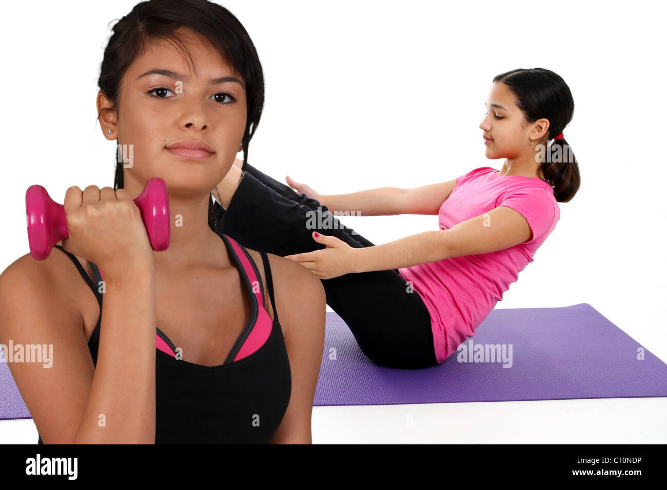 Girl Doing Yoga Pose in a Studio and another lifting weights Stock Photo