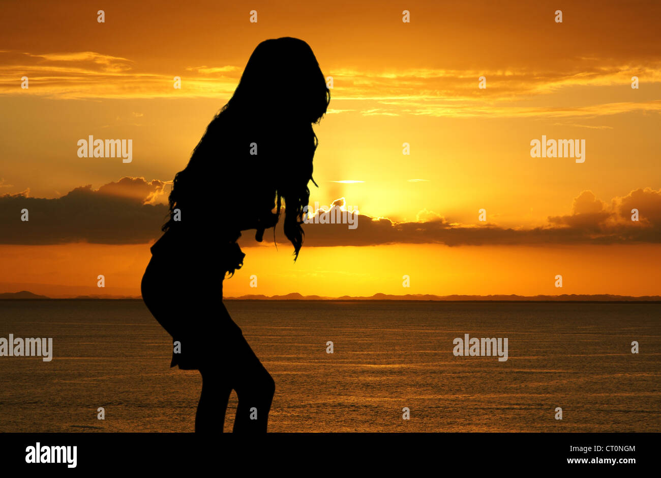 Woman standing on the beach watching the sunset Stock Photo - Alamy