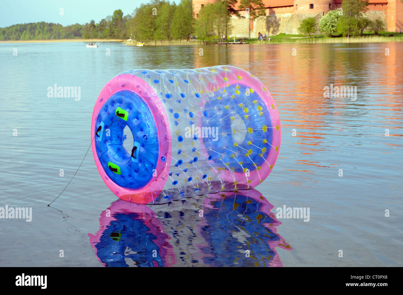 Zorbing air bubble on Lake Galve water near Trakai Castle. Floating boats and yachts. Active outdoor recreation. Stock Photo