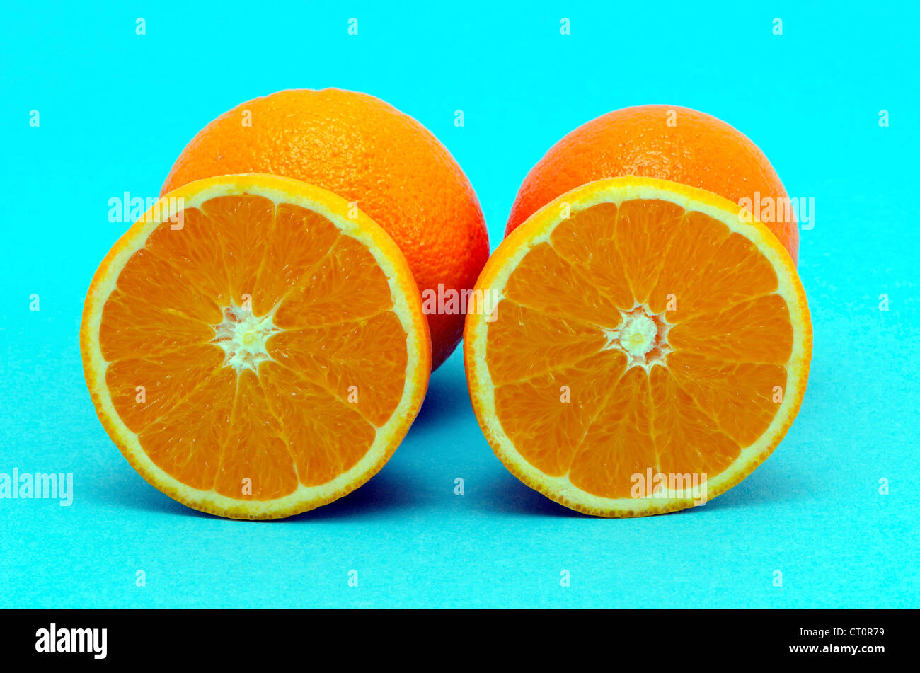 Oranges fruits full and sectioned on blue background. Healthy eating organic food items Stock