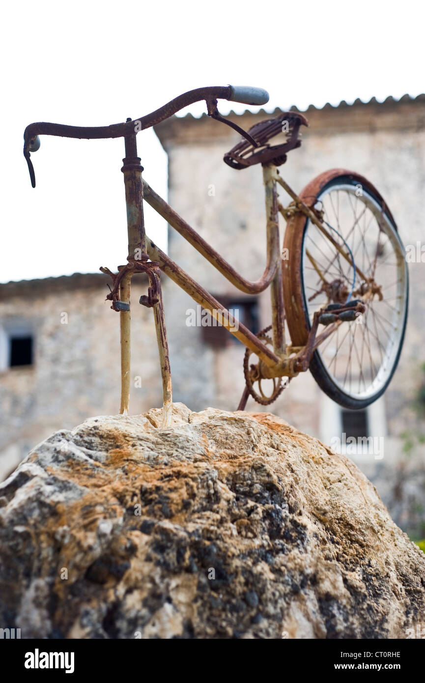Rusty bicycle built on a rock, contemporary sculpture. Stock Photo