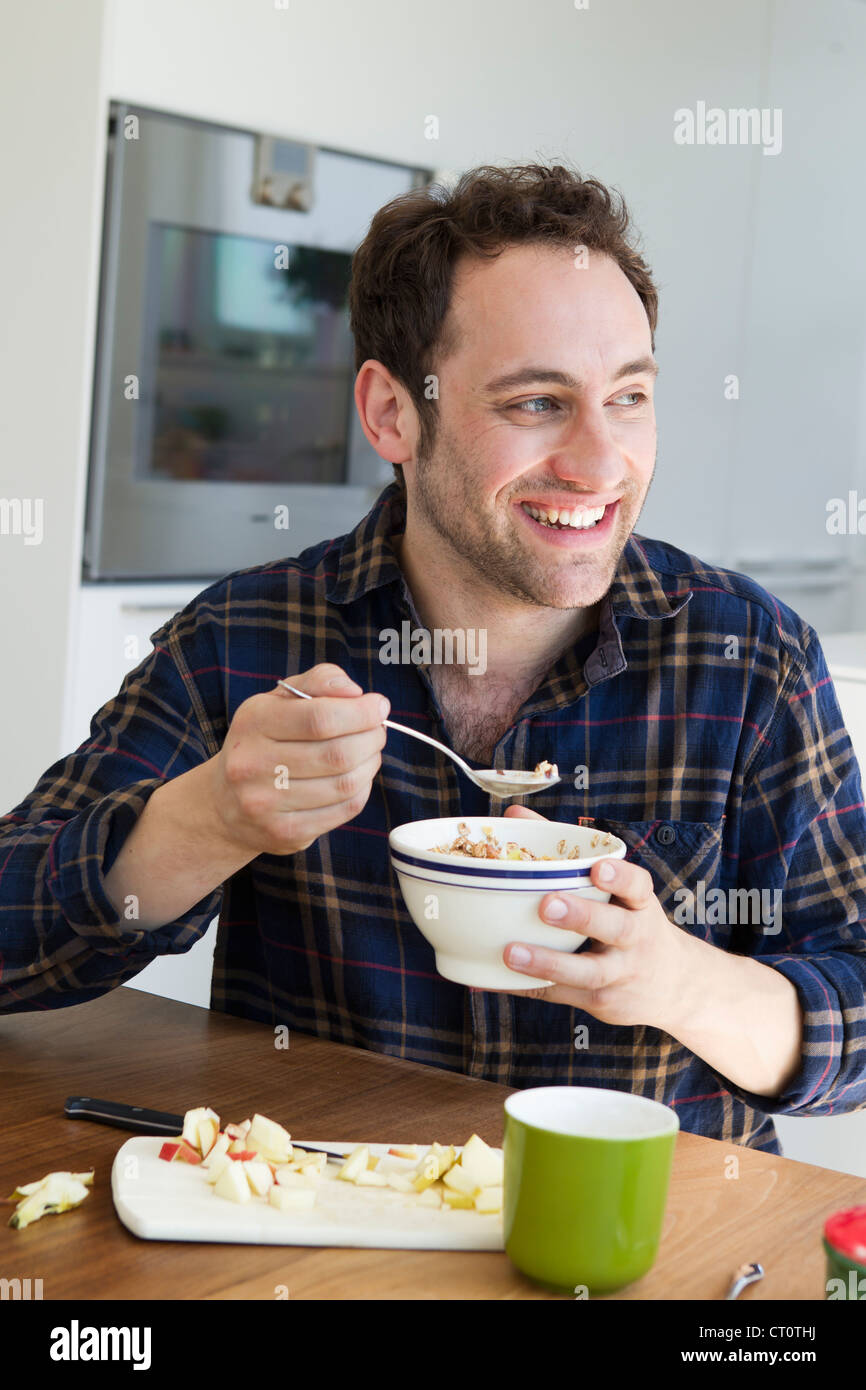 Smiling man eating bowl of cereal Stock Photo