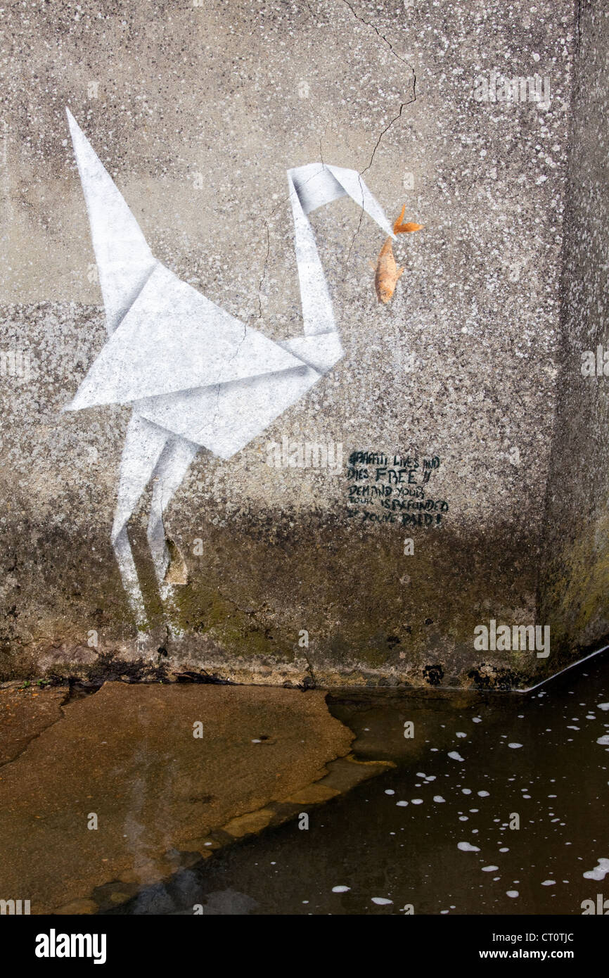 Grafitti by Banksy in Lyme Regis of an origami crane holding a fish in