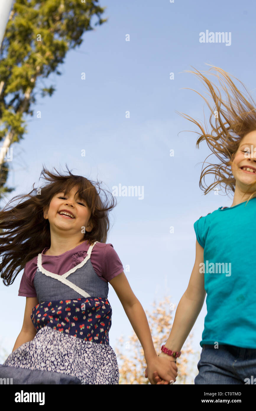 Smiling girls holding hands outdoors Stock Photo - Alamy