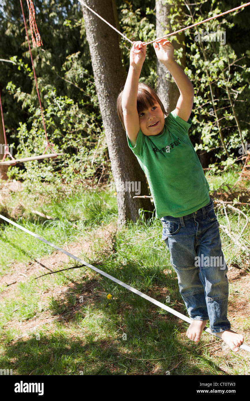 Boy playing on tightrope outdoors Stock Photo