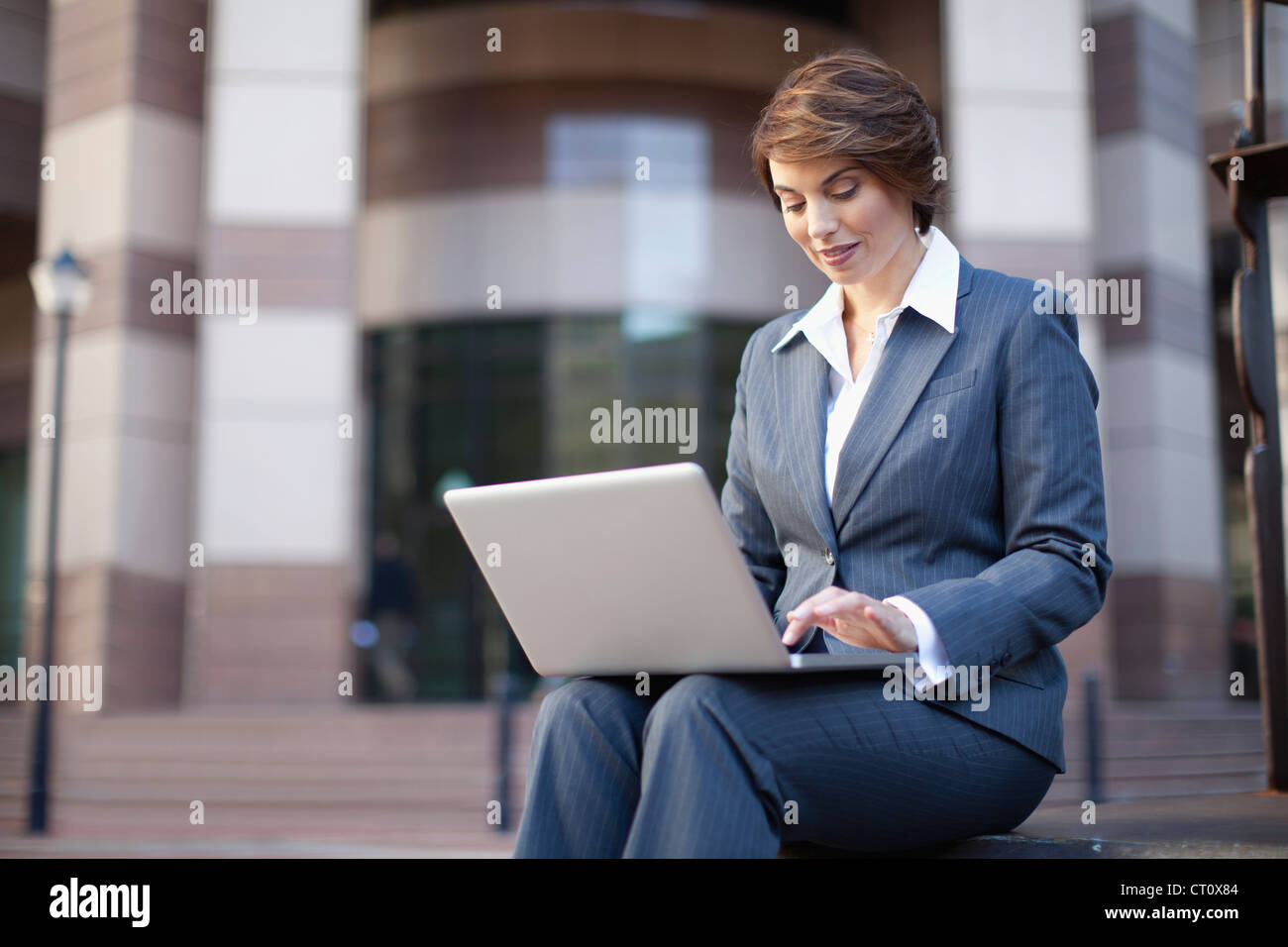 Businesswoman using laptop outdoors Stock Photo