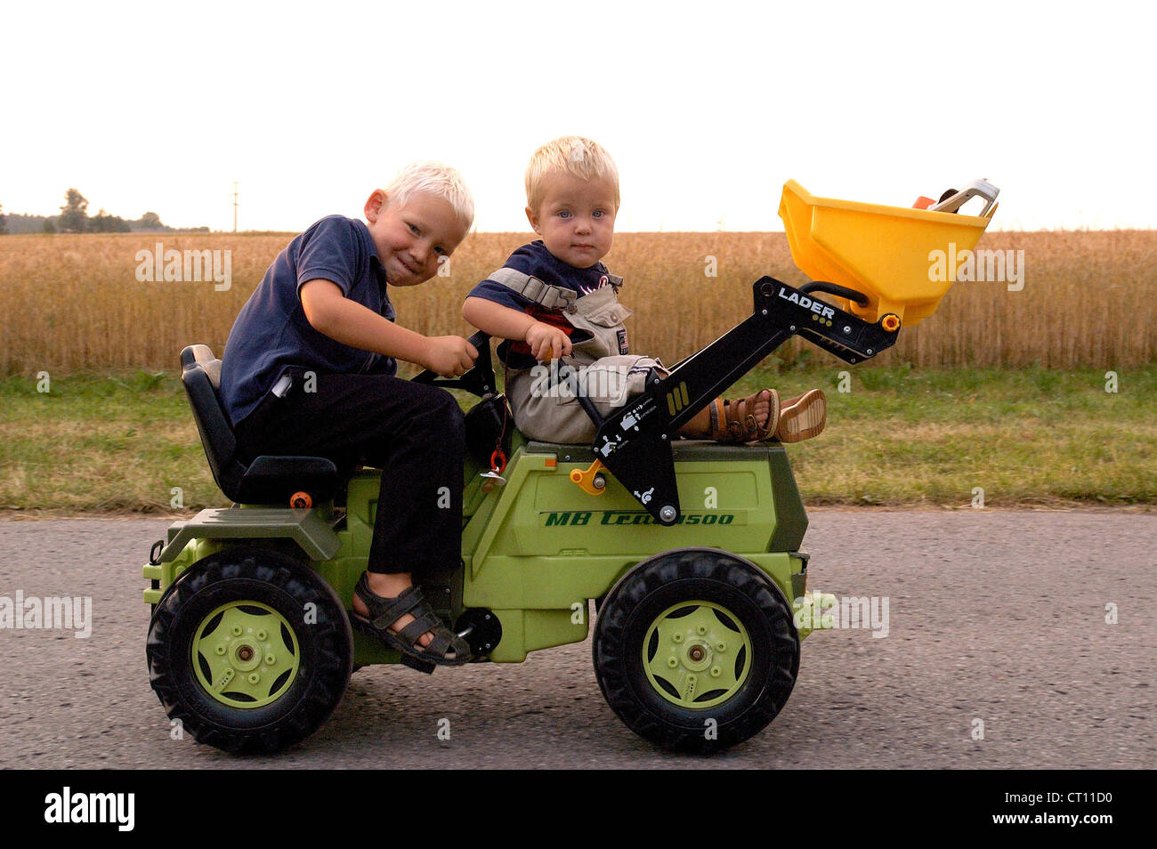 Children travel with a child's toy tractor Stock Photo