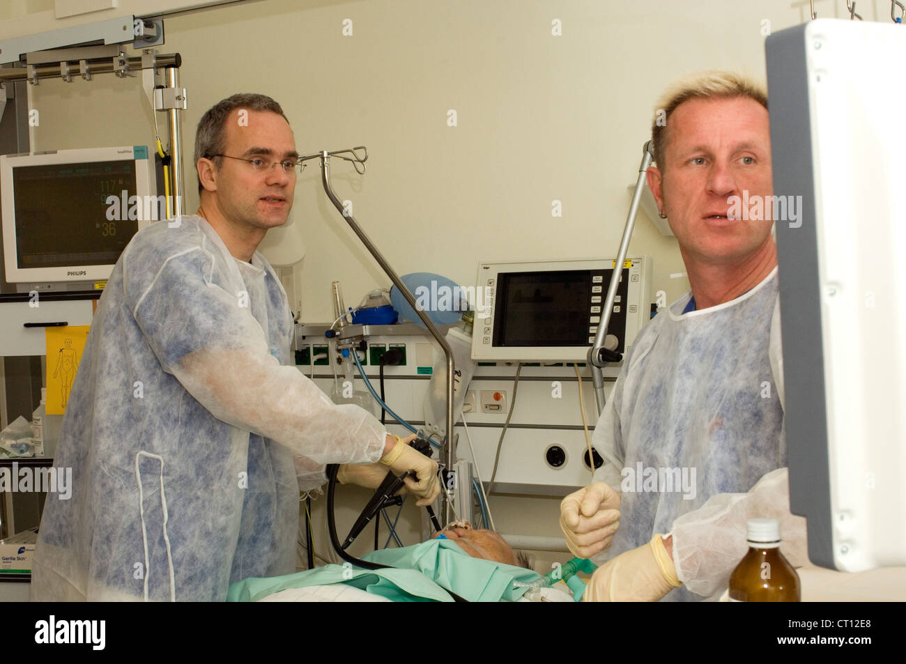 Surgeons using an endoscope to visually examine a patient's internal organs on a television monitor. Stock Photo