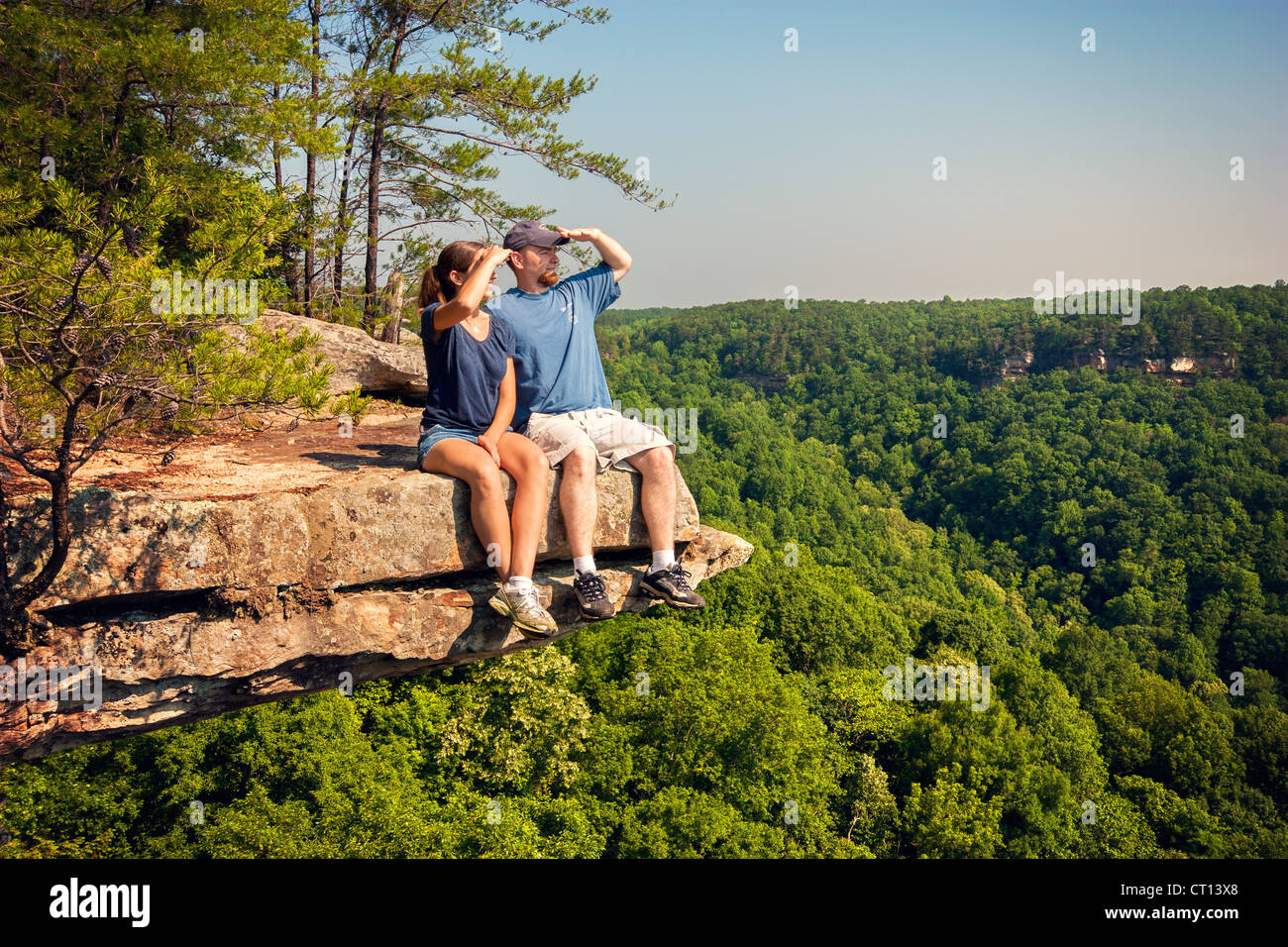 A man and woman sit on the edge of a cliff and take in the view Stock ...