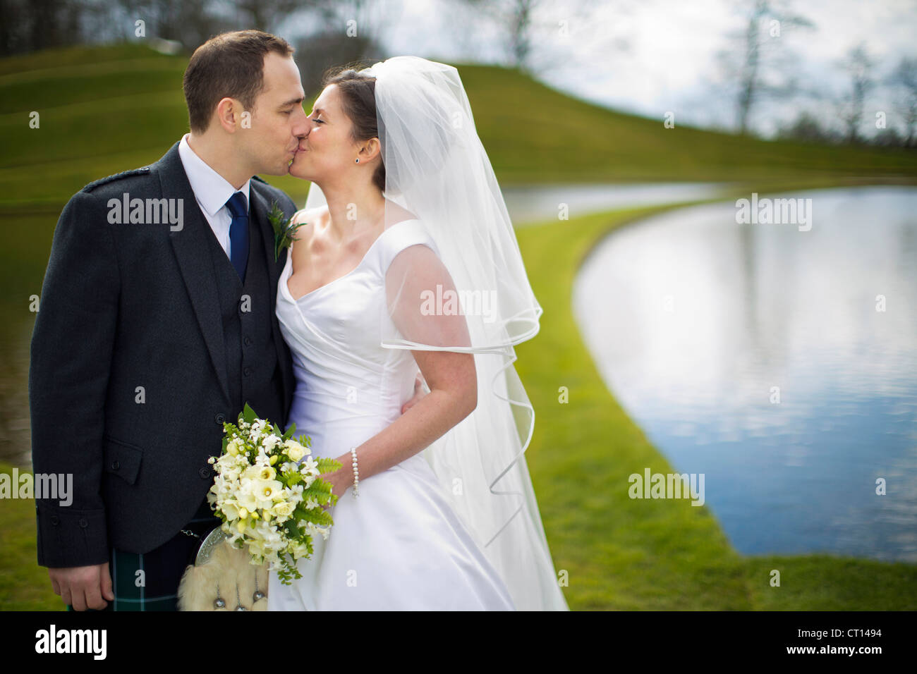 Newlywed couple kissing outdoors Stock Photo