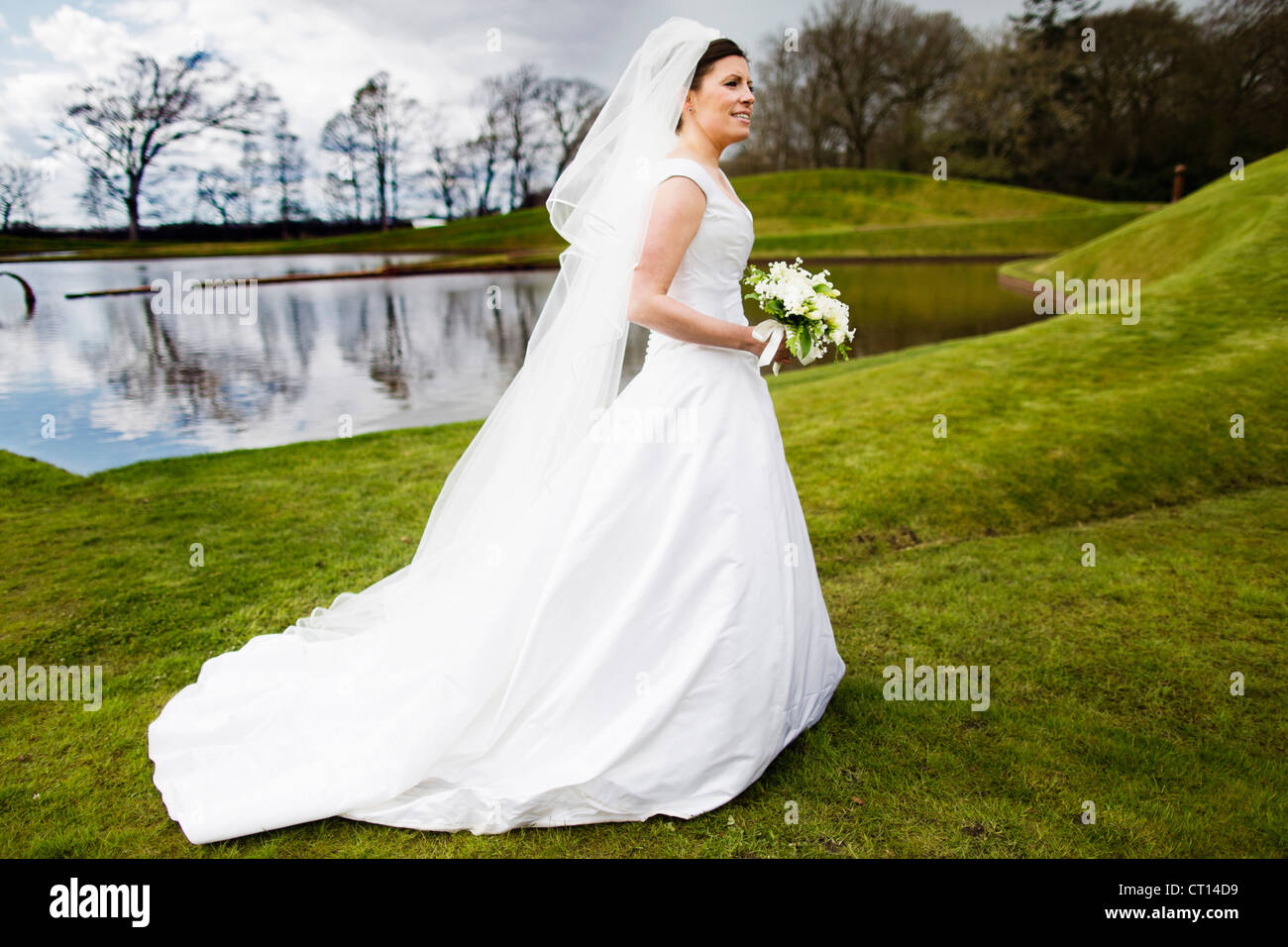 Smiling bride carrying bouquet outdoors Stock Photo - Alamy