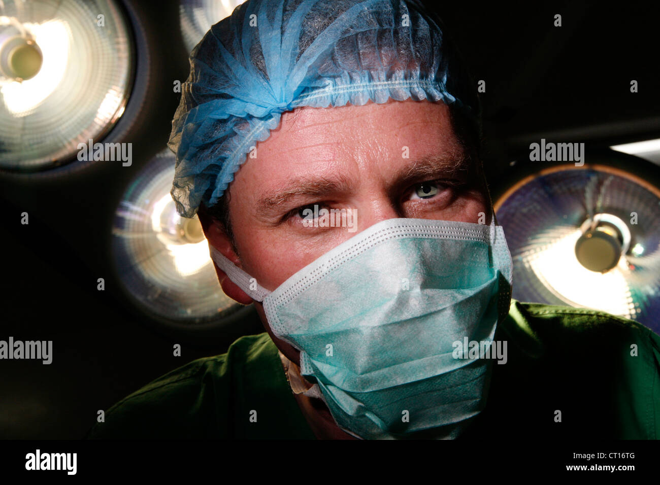 A fully masked surgeon underneath the theatre lights. Stock Photo