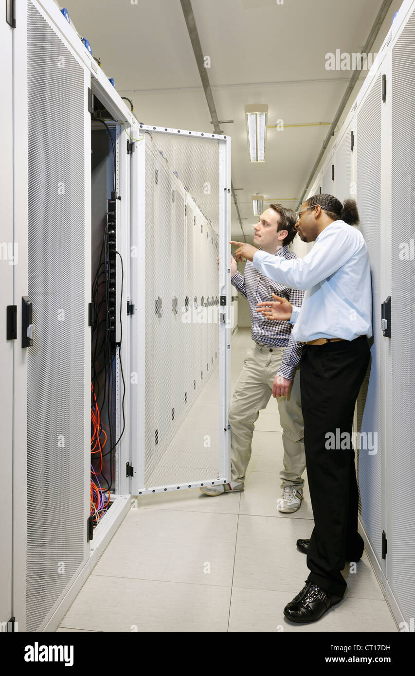 Businessmen examining wires in server Stock Photo