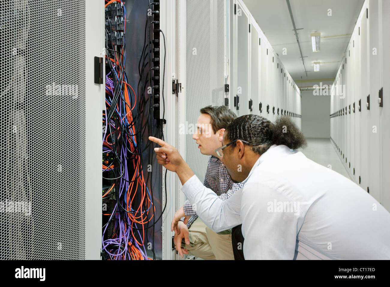 Businessmen examining wires in server Stock Photo