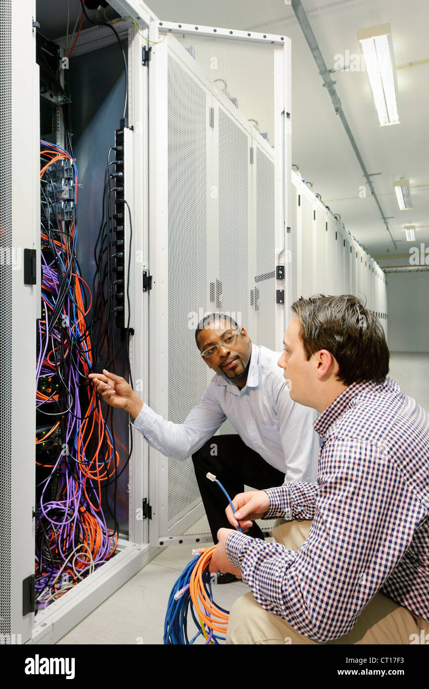 Businessmen examining wires in server Stock Photo