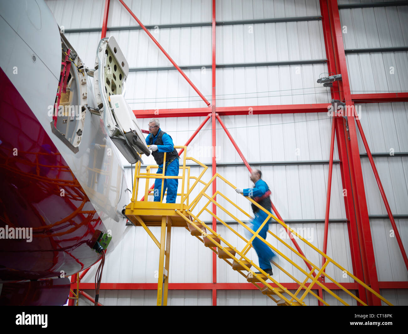 Workers examining airplane in hangar Stock Photo