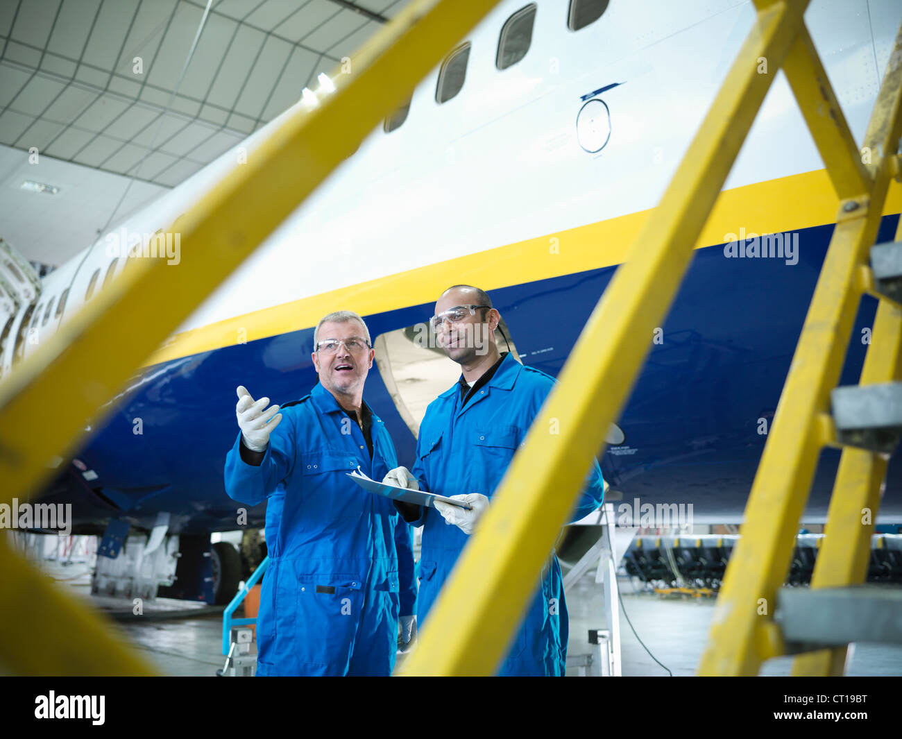 Workers talking in airplane hangar Stock Photo