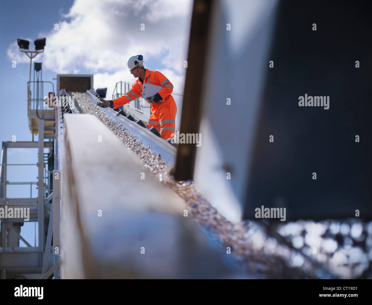 Worker examining stones on conveyor belt Stock Photo