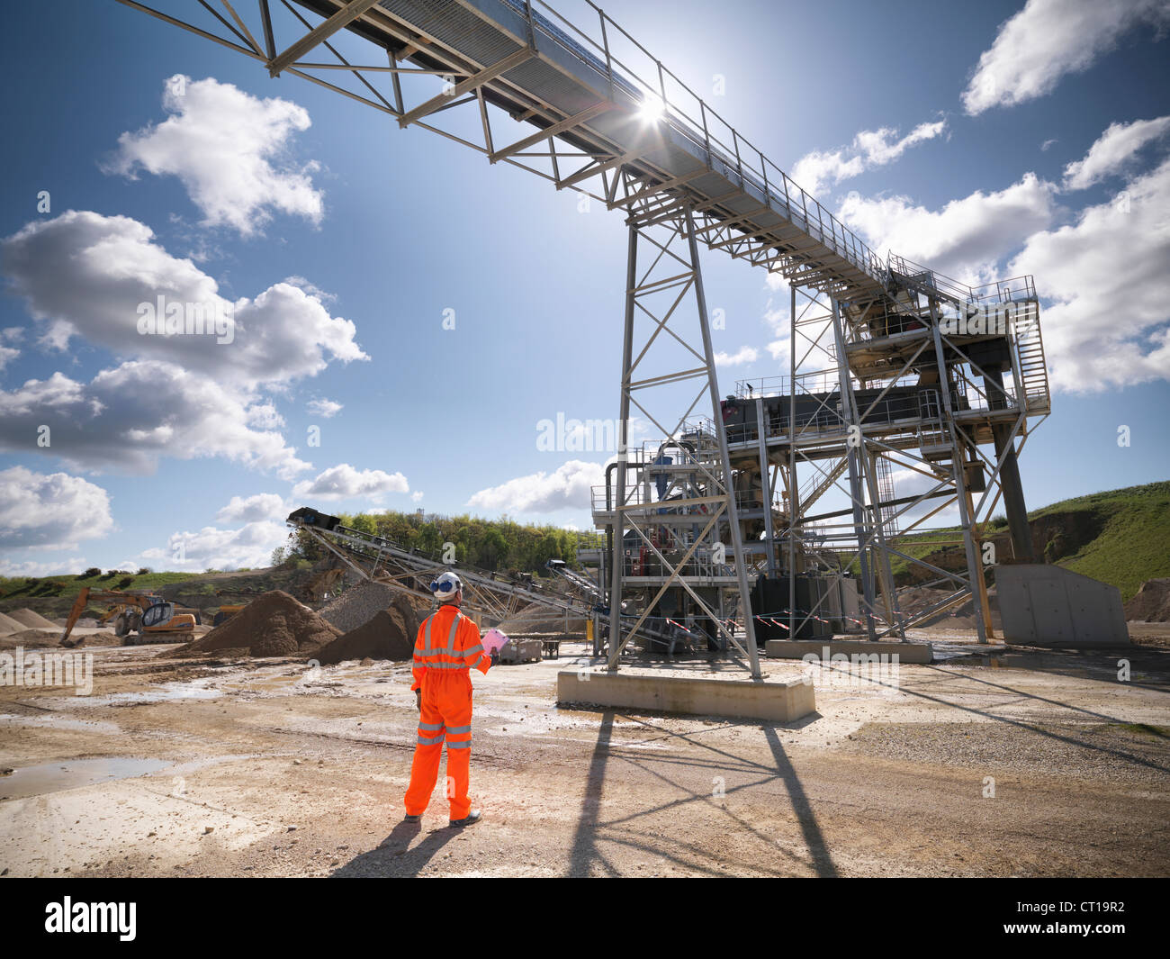Worker standing under conveyor in quarry Stock Photo