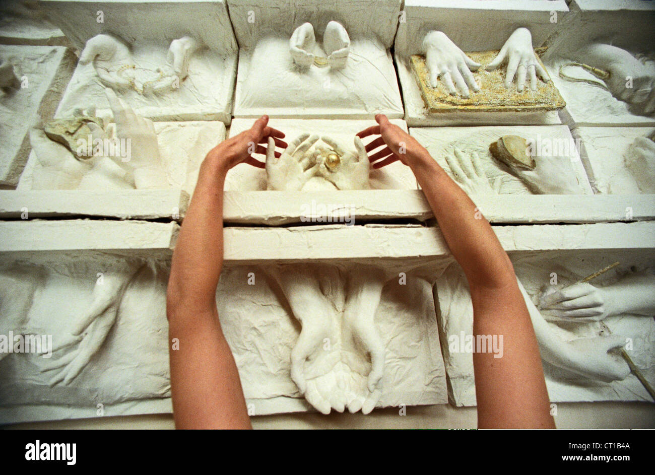 A woman artist arranging plaster casts of womens hands symbolising Work of Women in the World is Worth its Weight in Gold Stock Photo