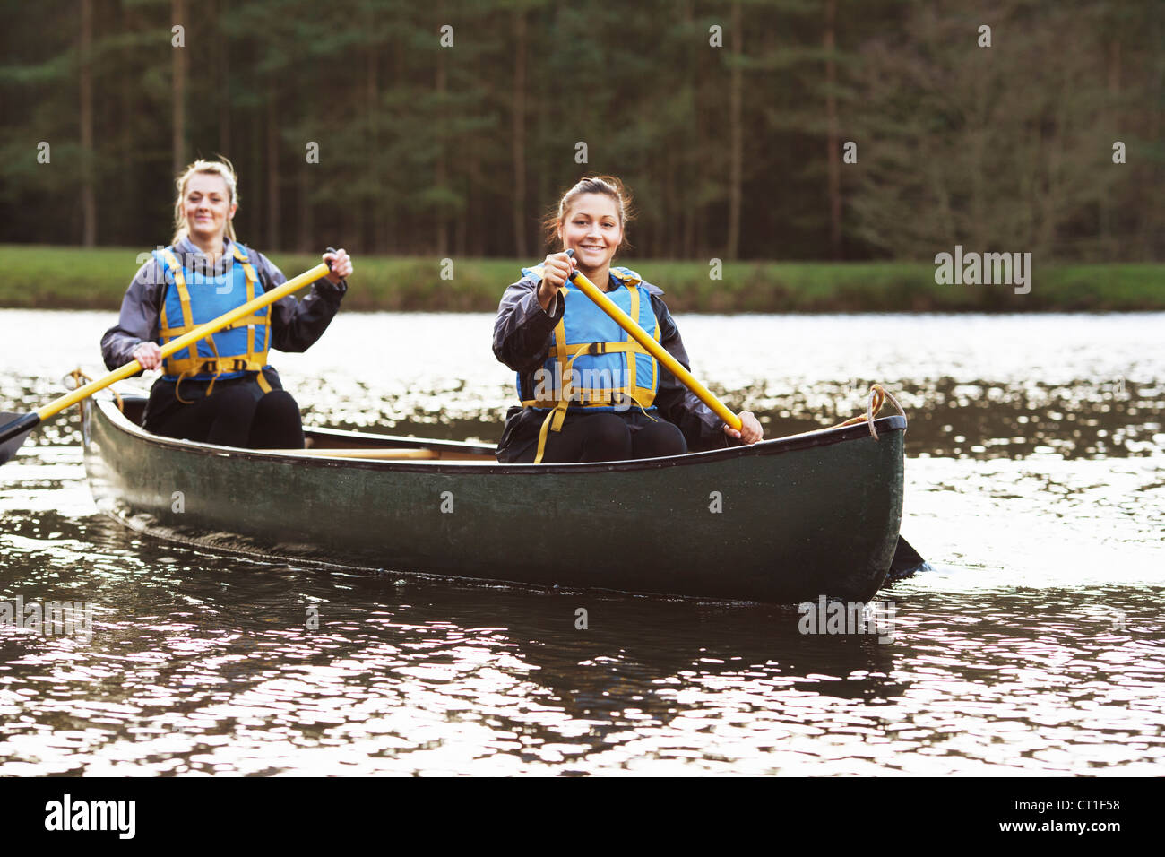Women rowing canoe on still lake Stock Photo