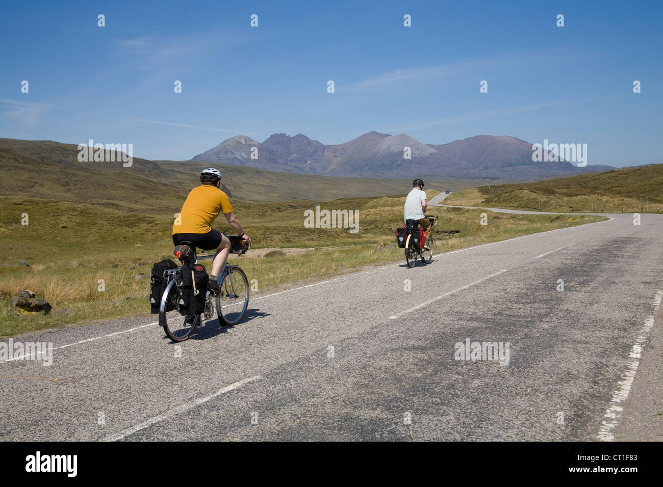 Scottish Highlands May Two male cyclists cycling along quiet road through mountains Stock Photo